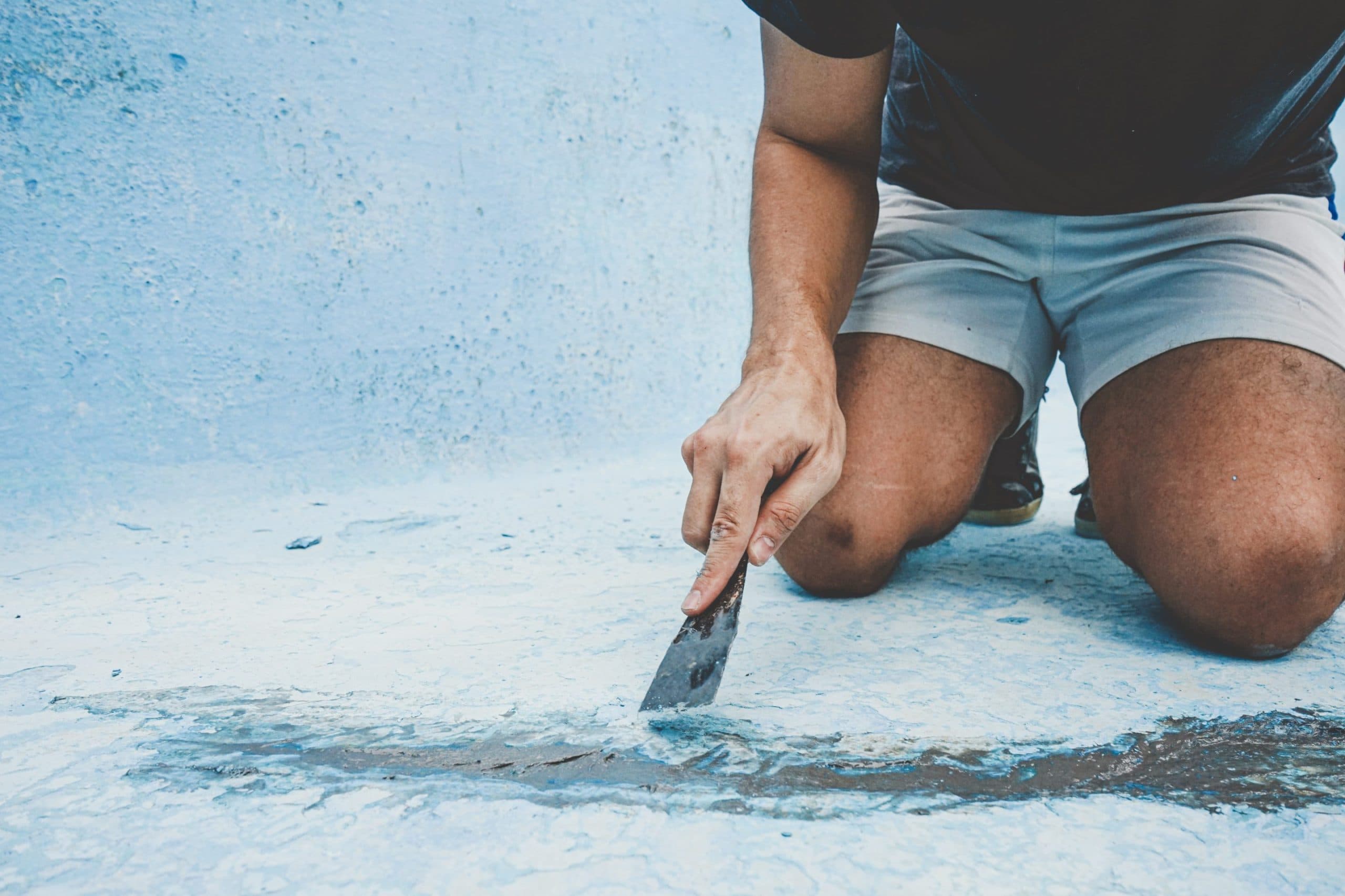 primer plano de un hombre reparando el piso de una piscina