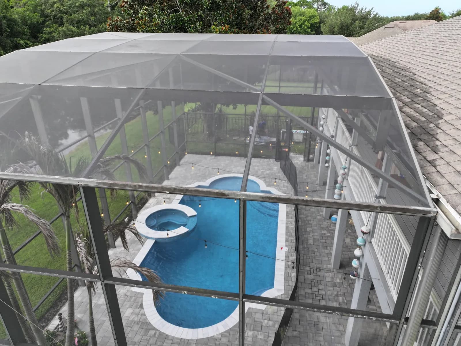 Finished pool with an attached spa inside a screened pool enclosure