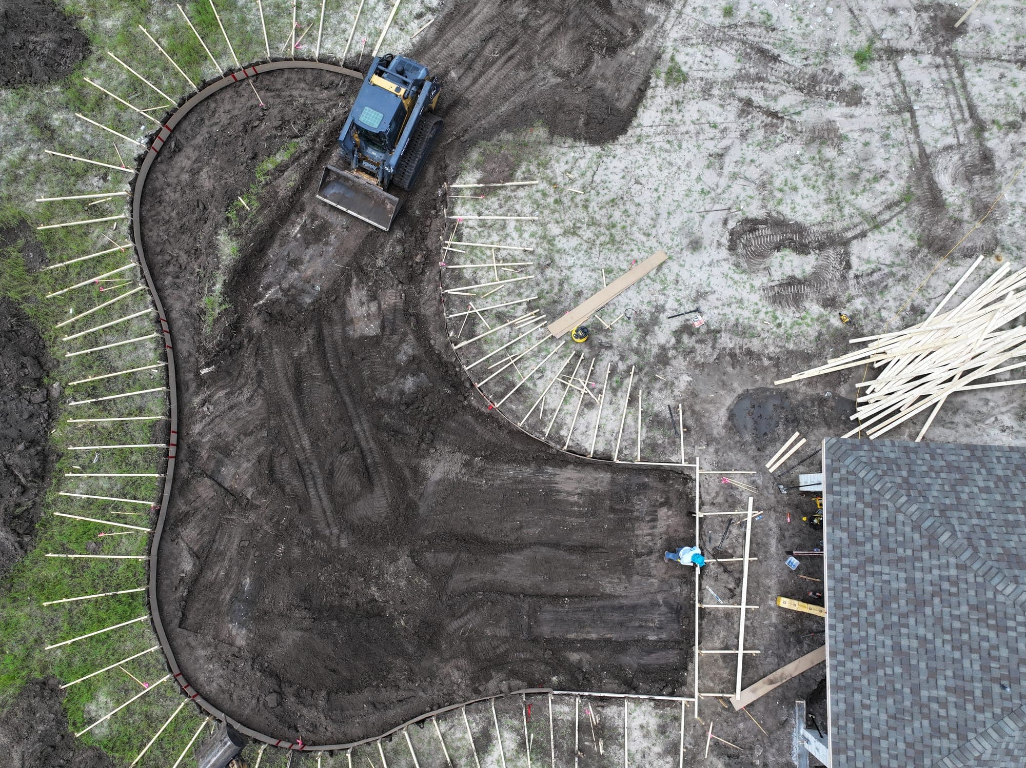 Aerial view of a dozer excavating a freeform pool inside the staked layout