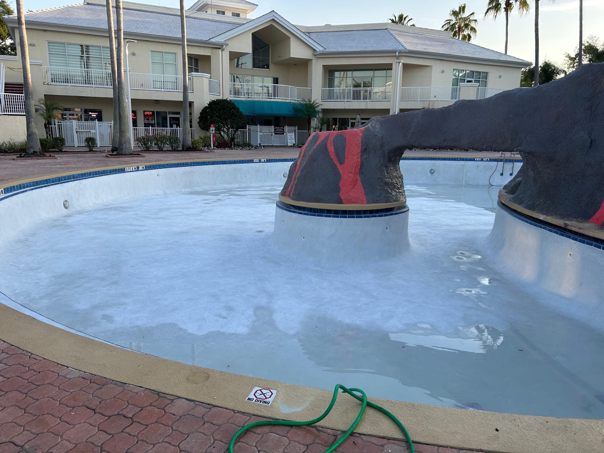 Commercial pool with a volcano feature and a fresh white finish, being filled