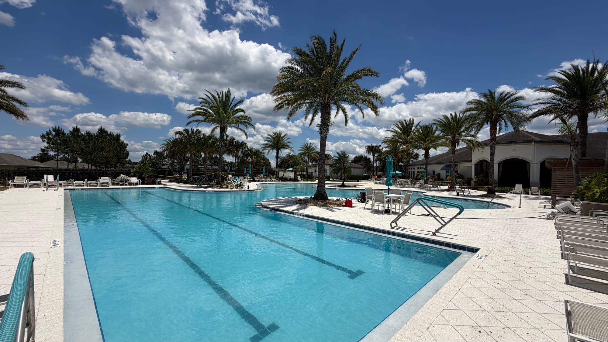 Finished community pool with lap lanes, palm trees and lounge chairs