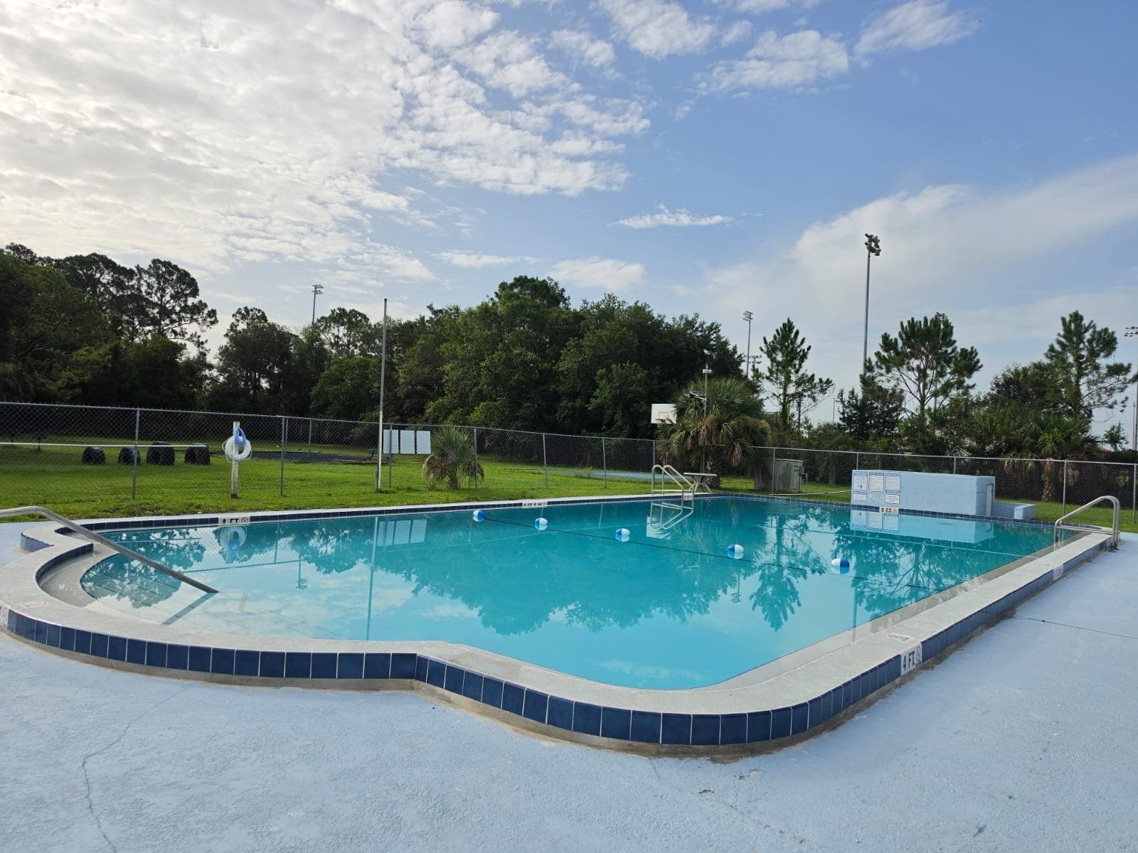 Piscina comunitaria con azulejo azul en la línea de agua y una terraza amplia de concreto