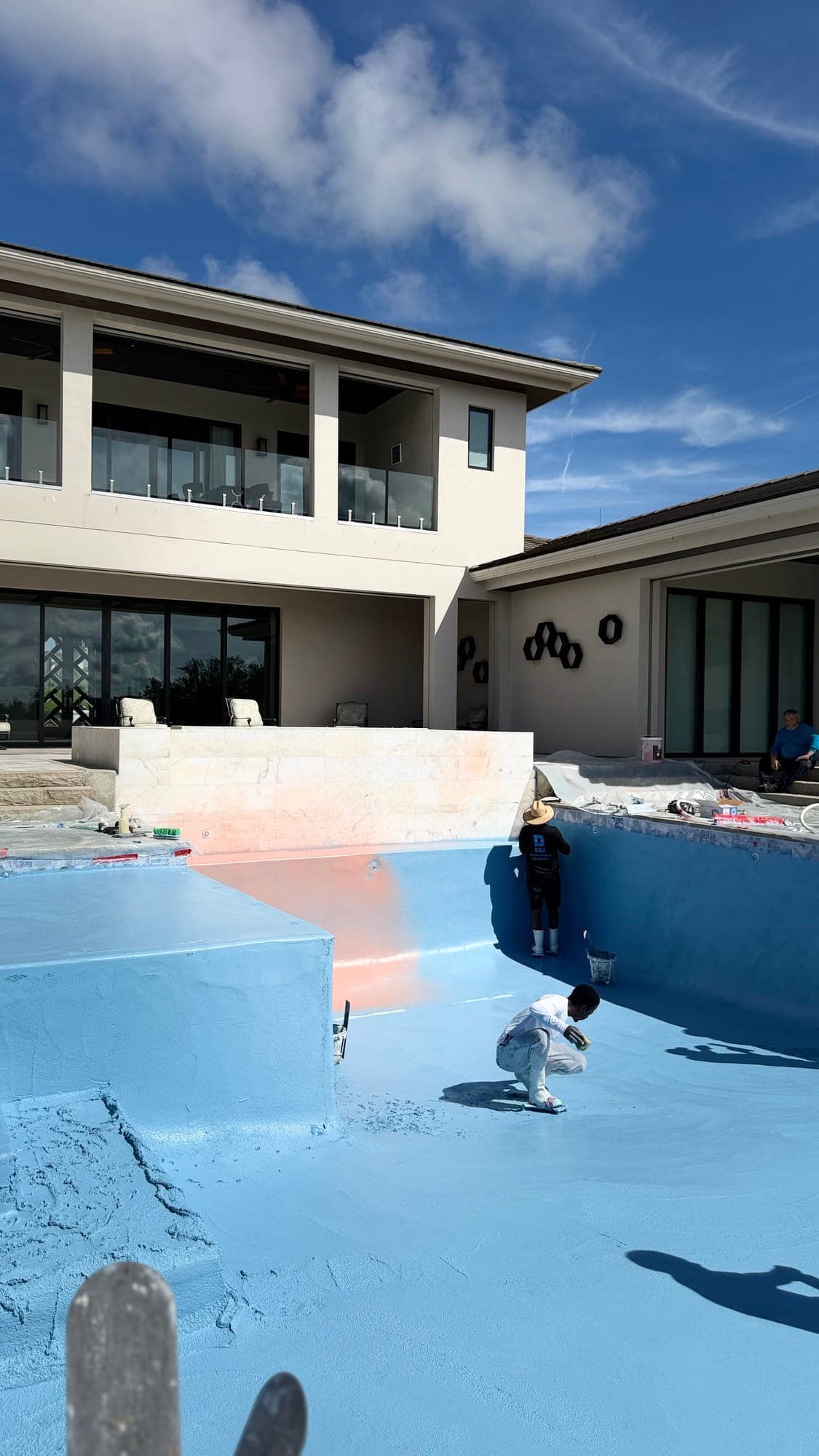 Miembro del equipo de D&J trabajando dentro de una piscina vacía, detrás de una casa de dos pisos