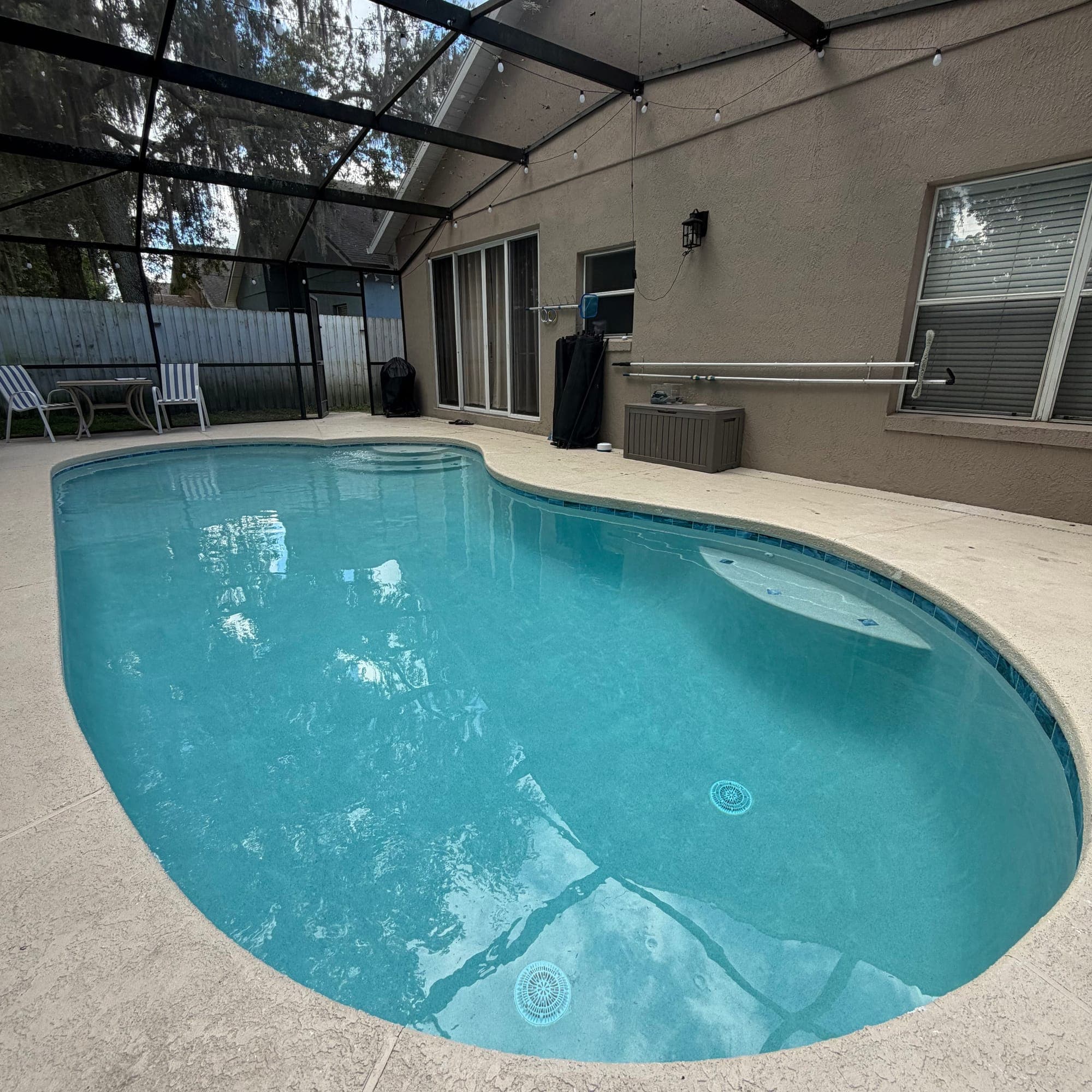 Piscina en forma de riñón bajo screen, con acabado liso azul claro