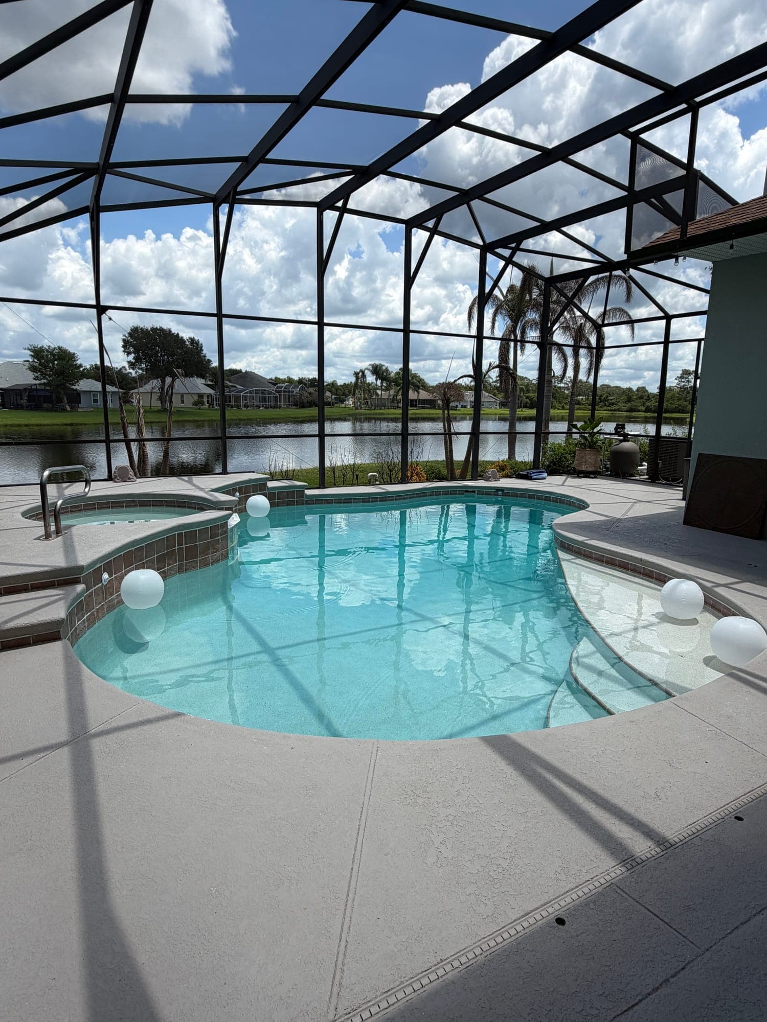 Piscina y spa bajo screen con vista a un lago