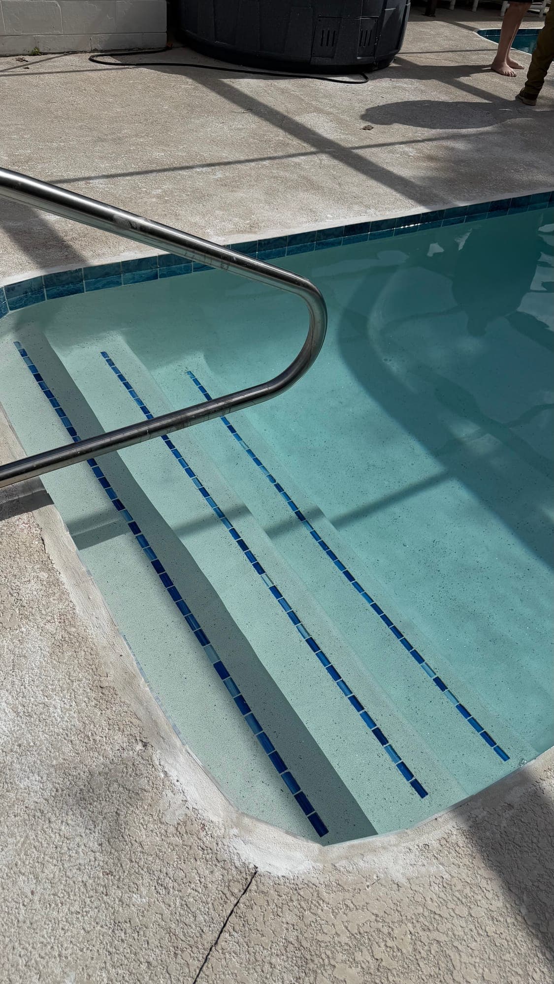 Escalones con línea de azulejo azul y pasamanos de acero
