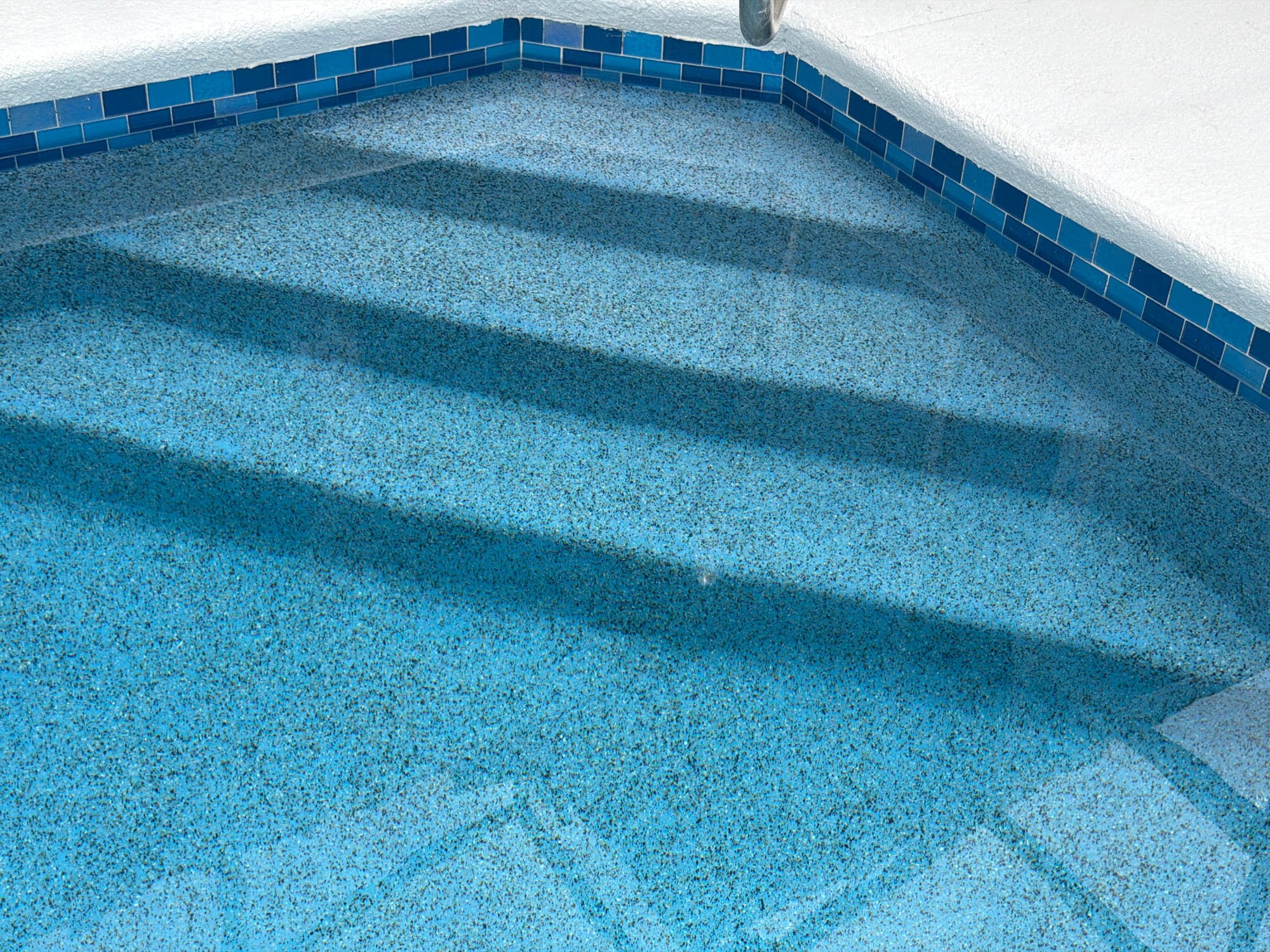 Escalones con acabado de piedrita y borde de azulejo de vidrio azul