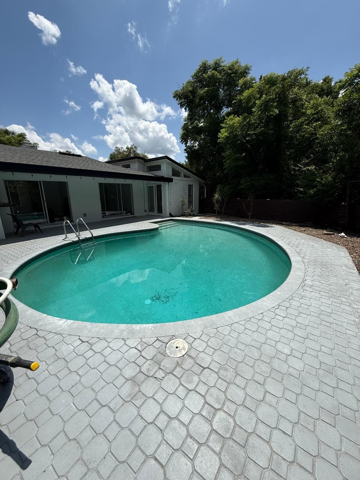 A round pool before resurfacing, with a gray paver deck