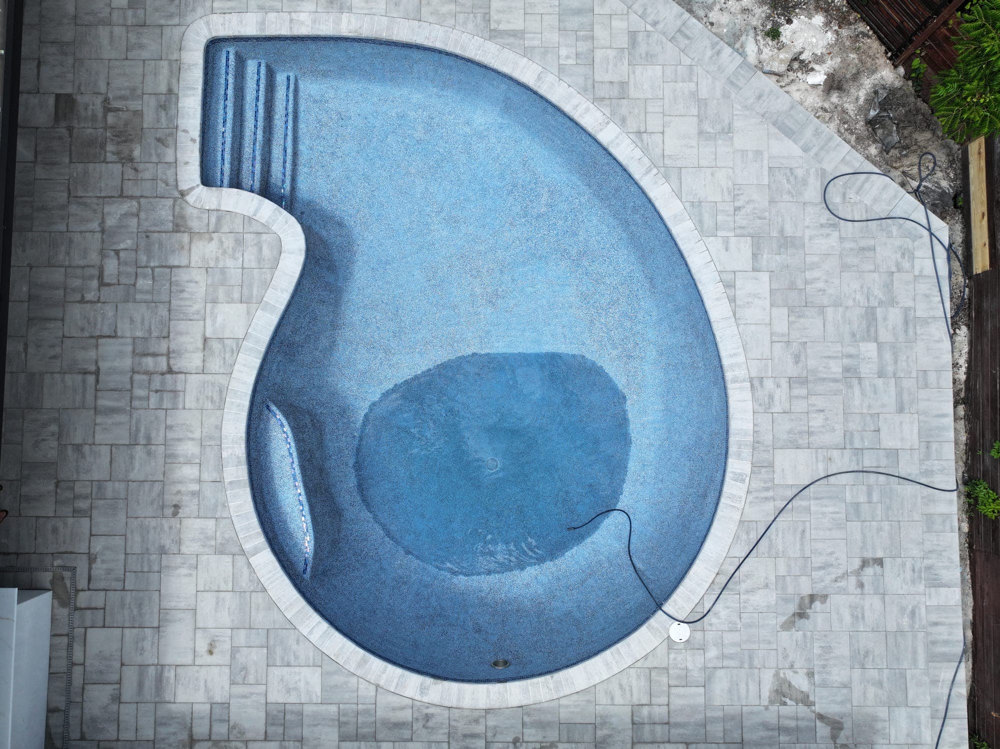 Aerial view of a pool being drained, with water left only in the deep end