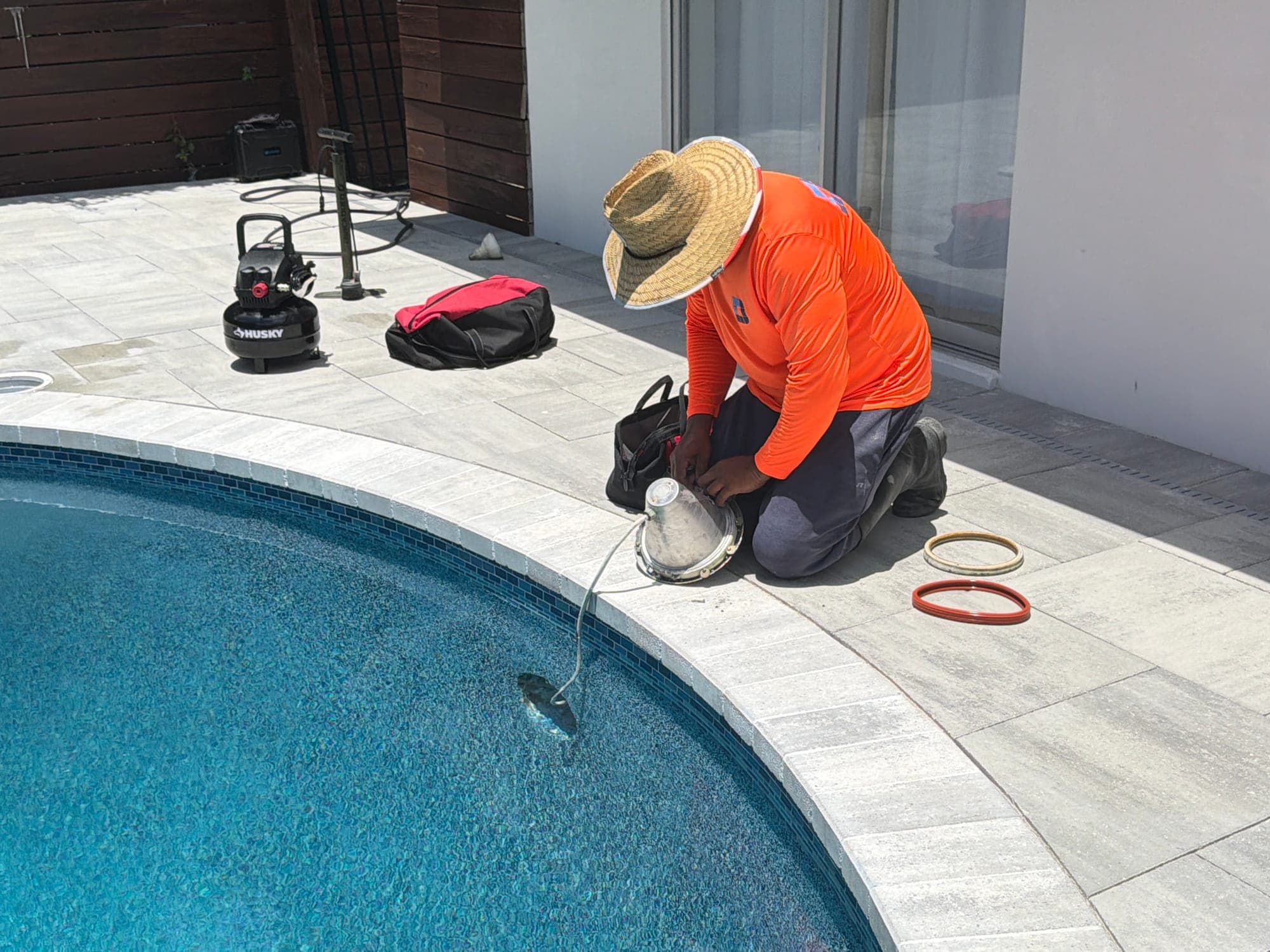 D&J crew member installing a new pool light fitting at the edge of the pool