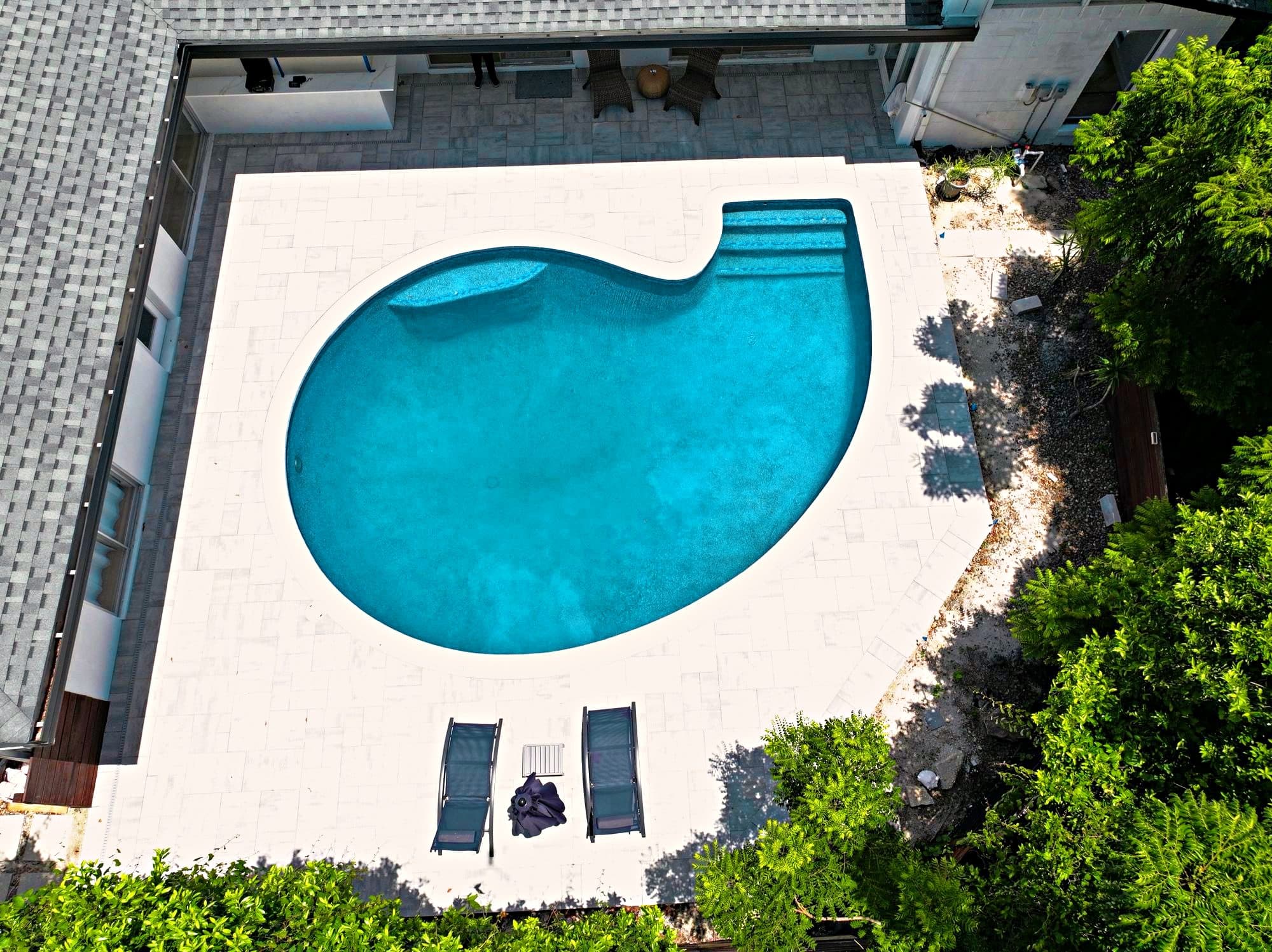 Vista aérea de una piscina terminada con deck nuevo de adoquines