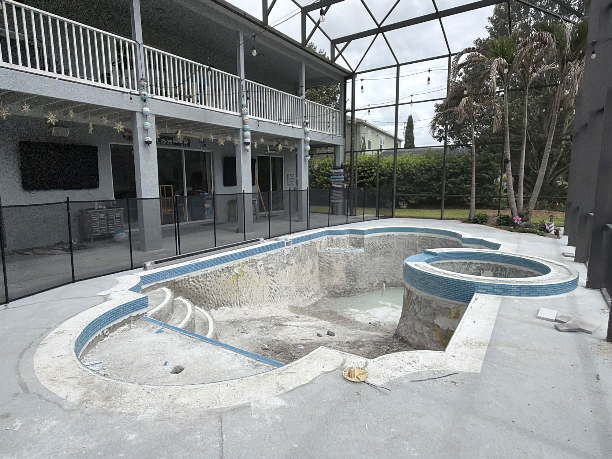 Piscina vacía bajo un screen enclosure, en plena renovación