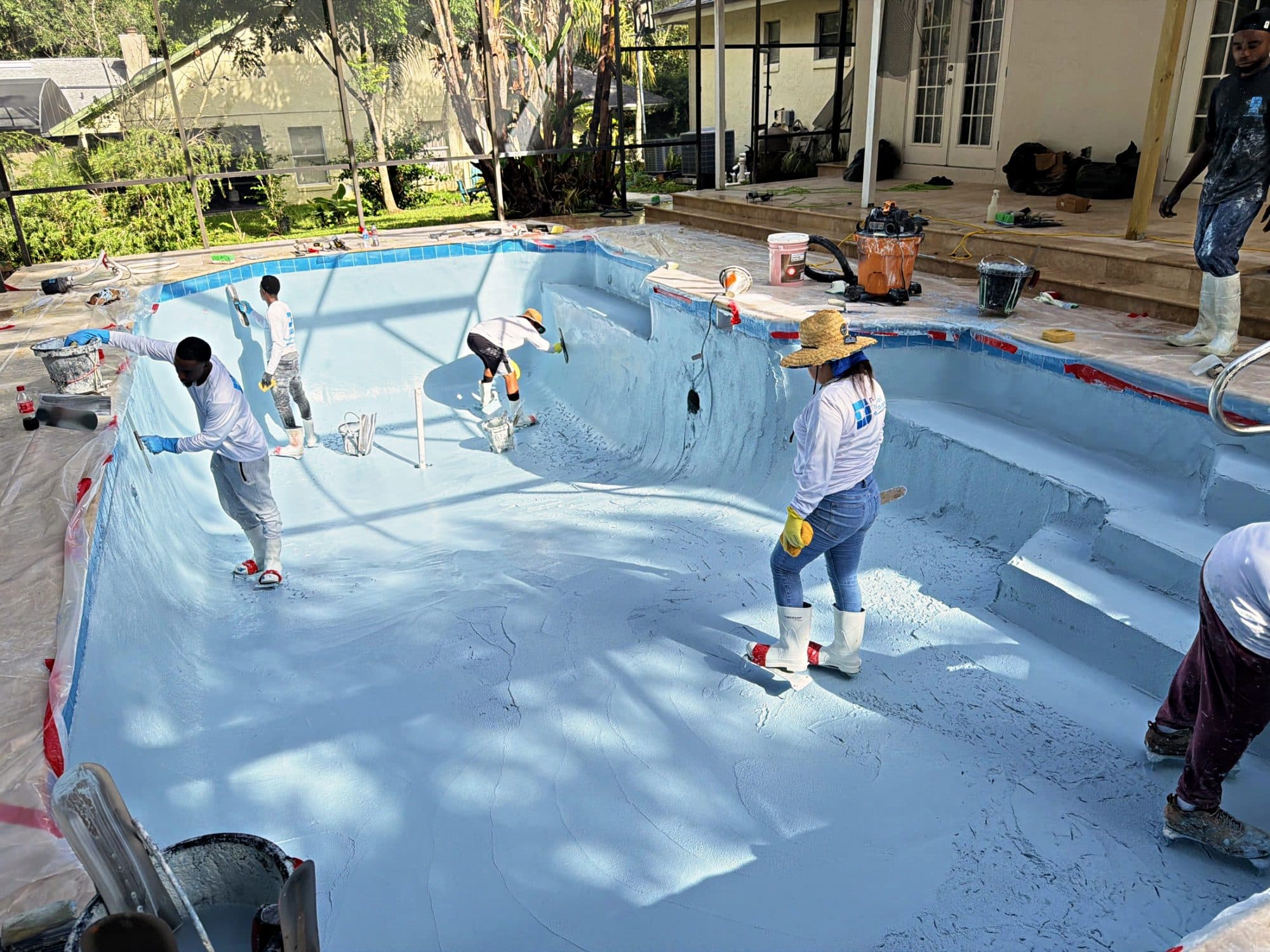 Equipo extendiendo el acabado nuevo en el piso de la piscina