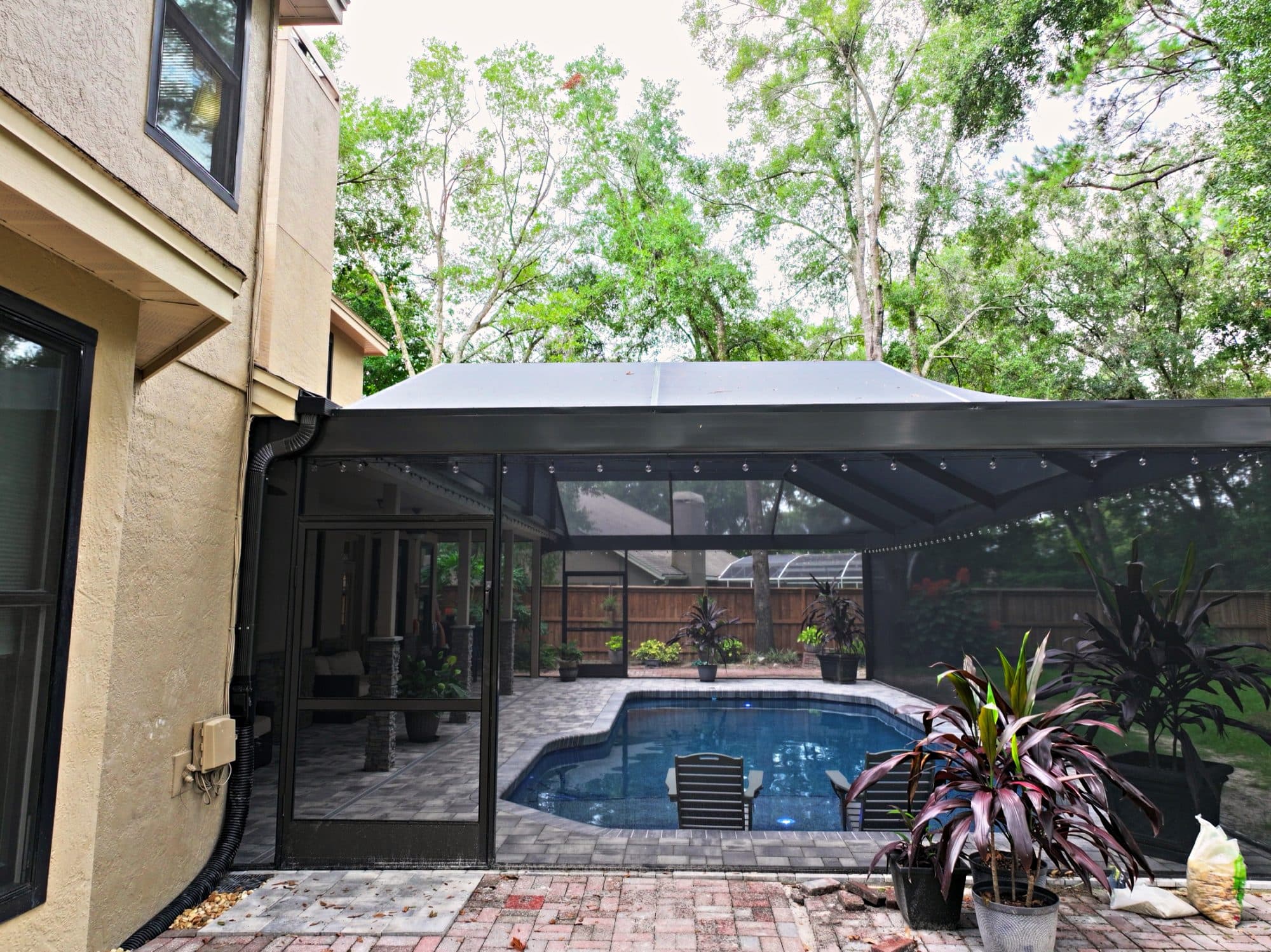 Piscina en el patio con deck de adoquines bajo un screen enclosure en el centro de la Florida